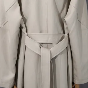 Dettaglio posteriore di un elegante trench beige lungo con cintura annodata in vita