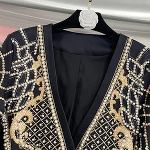 Dettaglio ravvicinato di squisiti ricami in perle e motivi dorati su un blazer nero