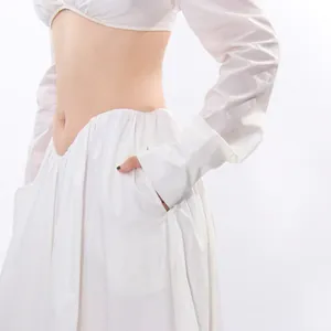 Close-up detail showing the waistline of a white cropped top and pleated maxi skirt set