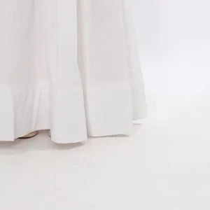 Macro view showing the elegant hemline of a white summer long skirt in a clean studio