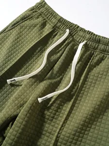 Macro view of olive green waffle knit fabric and drawstring detail on men's pants