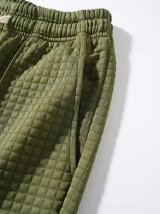 Close-up of green waffle knit jogger pants showing pocket and elastic waistband detail.