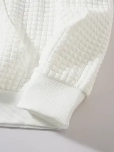 Nahaufnahme der weißen Waffelstruktur und des elastischen Rippbündchens am Sweatshirt