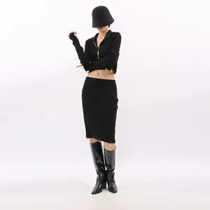 Black two-piece knit set with cropped zip-up top, midi skirt, and gold charms decoration.