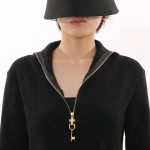 Close-up of a vintage black ribbed knit top featuring a unique gold key-shaped zipper