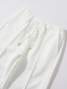 Close-up macro view of white waffle textured casual trousers with elastic drawstring waist