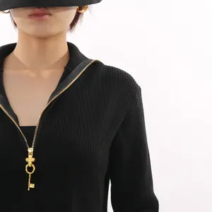 Close-up detail of black ribbed knit top featuring a vintage golden key-shaped zipper puller.