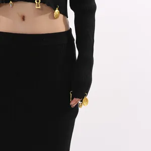 Close-up of black ribbed knit crop top featuring decorative gold charms on cuffs