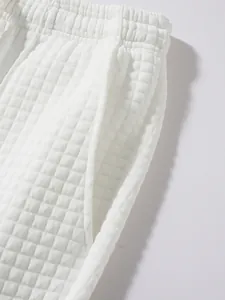 Detailed close-up of white waffle knit pants showing elastic waistband and side pocket
