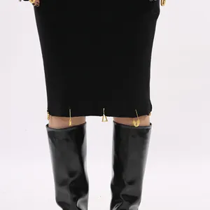 Close-up detail view of black ribbed knit skirt hem with decorative gold safety pin charms