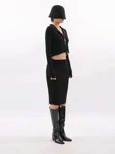 Elegant black knit two-piece set with cropped top and pencil skirt featuring gold charms