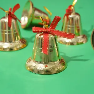 Primer plano de campanas de Navidad doradas con lazos rojos sobre fondo verde.