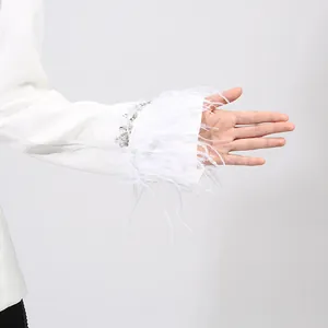 Close-up of white blazer sleeve featuring elegant feather trim and rhinestone detailing
