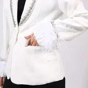 Close-up of white blazer with elegant rhinestone and feather trim on sleeve cuffs.