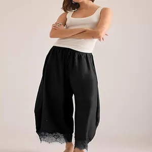 Détail montrant l'ourlet en dentelle délicate sur ce pantalon noir à coupe courbe