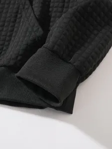 Detailaufnahme von schwarzem Waffelstoff und Rippbündchen an einem Herren-Sweatshirt