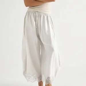 Vue détaillée du pantalon court blanc à jambes larges avec bordure en dentelle au bas.