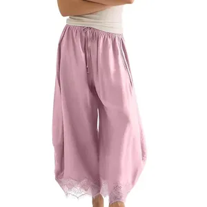 Détail d'un pantalon rose ample avec ourlet en dentelle et taille à cordon