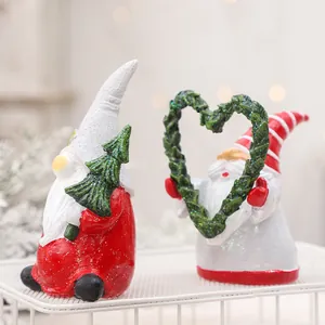 Coppia di statuette di gnomi natalizi in resina con glitter e corona a forma di cuore.