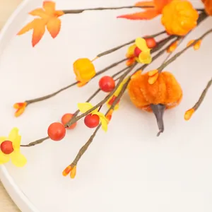 Ramo decorativo autunnale con mini zucche, foglie di acero arancioni e bacche rosse
