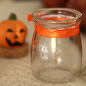 Festive Halloween glass candy jar with orange ribbon for party table decoration