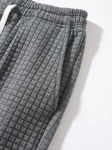 Close-up of gray waffle textured sweatpants with waistband drawstring and side pocket detail