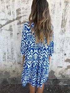 Back view of a stylish blue and white ikat print tiered dress for women outdoors.