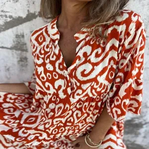 Close-up detail of a women's orange and white abstract print V-neck pleated summer dress