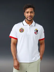 Detailed view of British royal embroidery on a men's white cotton Polo shirt.