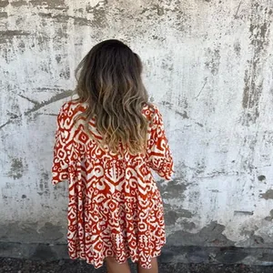 Back view of a bohemian red and white printed mini dress with tiered skirt detail