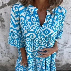 Detail view of a blue and white patterned V-neck summer dress with delicate pleating