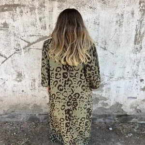 Vue arrière détaillée d'une robe longue verte à motif léopard contre un mur rustique usé