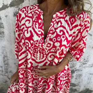 Detailed close-up of a women's V-neck pleated leisure dress with red and white abstract print