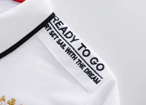 Macro view showing the shoulder embroidery detail on a white cotton Polo shirt for men