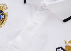 Detailed view of white cotton Polo shirt featuring royal crown embroidery and buttons