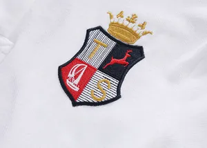 Close-up detail of the intricate embroidered royal crest on white cotton polo shirt