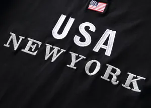 Detail view of high-quality white USA NEW YORK embroidery on black cotton Polo shirt fabric