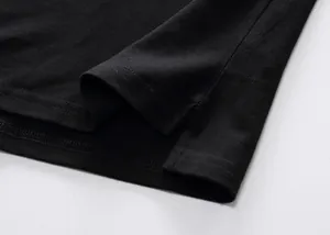 Detail view of the side vent and stitching on a black cotton piqué polo shirt
