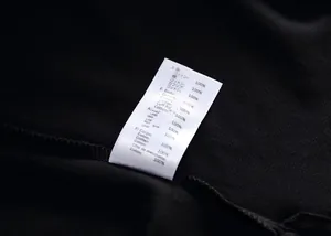 Detail view showing the 100% cotton material wash care label on a black polo shirt.