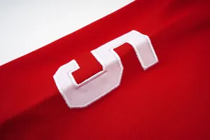 Κοντινό πλάνο λευκού κεντημένου αριθμού 5 σε κόκκινο βαμβακερό αθλητικό μπλουζάκι πόλο.