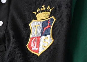 Detailed macro shot of the embroidered crest on a British style cotton polo shirt.