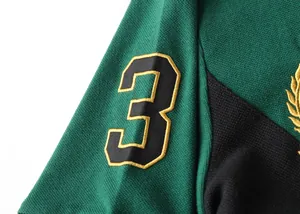 Detailed view of the embroidered number three on a green and black polo shirt sleeve