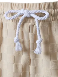 Close-up detail of white rope drawstring and beige checkered jacquard fabric texture
