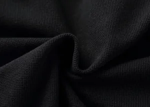 Macro shot showing the breathable black pique cotton fabric texture of a men's polo shirt.