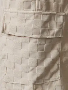 Macro detail of beige checkerboard jacquard fabric on men's summer casual shorts.