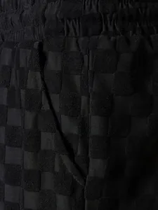 Macro view of black checkerboard jacquard fabric and pocket detail on men's leisure shorts