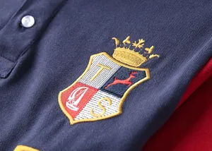 Close-up of British style embroidery crest on navy blue cotton piqué polo shirt