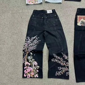 Vista macro dettagliata dell'intricato ricamo di fiori di ciliegio rosa su jeans neri.
