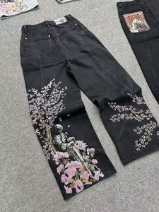 Dettaglio dei jeans neri VESCARTES con intricati ricami di fiori di ciliegio e del cavaliere.