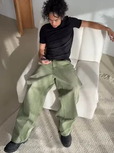 Male model wearing loose matcha green wide-leg jeans in a minimalist interior setting